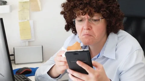 Woman at office on a workplace eats a hamburger Video stock 114610186