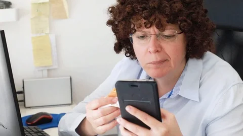 Woman at office on a workplace eats a hamburger Video stock 114610198