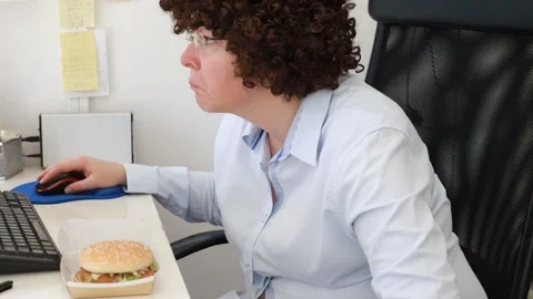 Woman at office on a workplace eats a hamburger Video stock 114611062