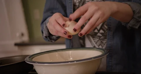 Woman opening a cracked egg over bowl in prep kitchen Stock Footage 123737252