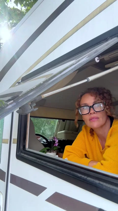 Woman opening the window of a camper van Stock Footage 344856483