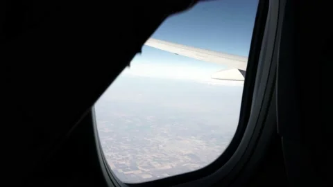 Woman Opens Airplane Window with Wing and Ground in Focus Stock Footage 146160106