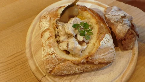 Woman opens bread lid stirs and eats mushroom soup in pita in restaurant.  Stock Footage 142256302