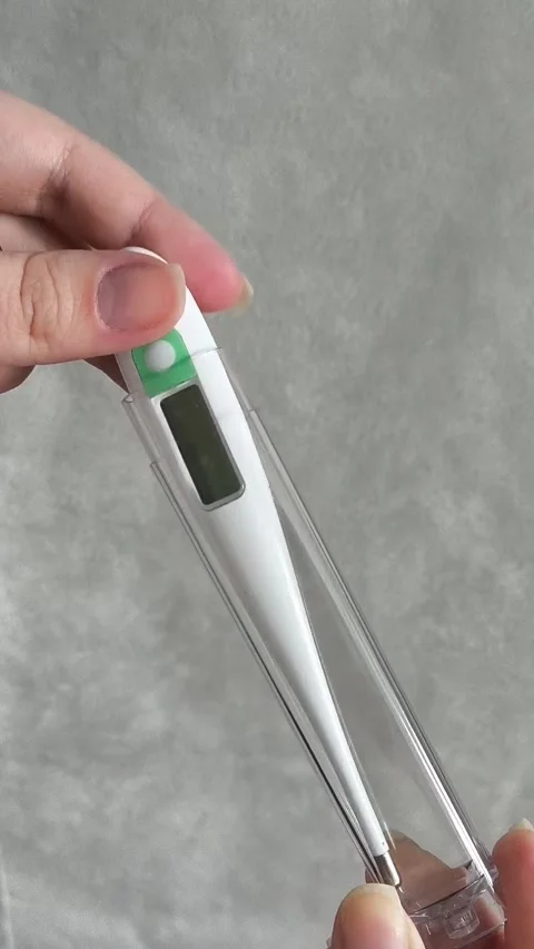 A woman opens a container with an electronic thermometer and turns it on Video stock 325289128
