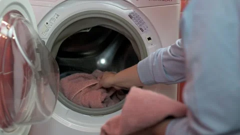 Woman opens front-loading washing machine and takes out freshly washed towels Видео 291273522