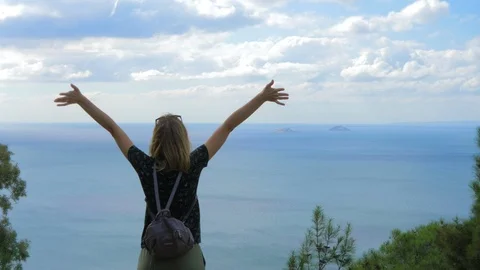 Woman opens her arms while standing in front of the sea Stock Footage 97115135