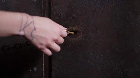 A woman opens a lock with a key on an old wooden shackle in a dark room. Stock Footage 291517193