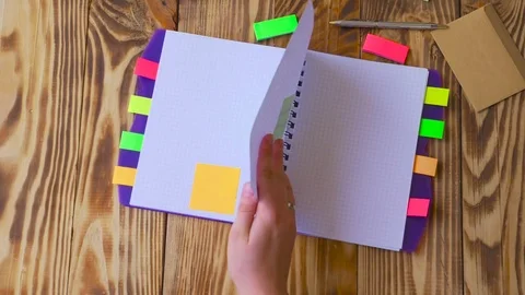 Woman opens notepad and thumbnails pages. Open notepad with office supplies. Stock Footage 77728240