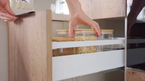 Woman opens pull out pantry drawer and removes container with oats Stock Footage 346182923