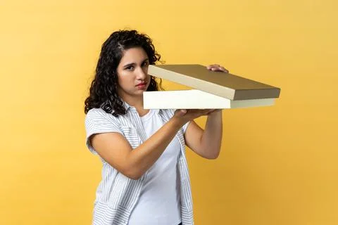 Woman opens wrapped present box, expressing disappointment, looking at camera Stock-Fotos