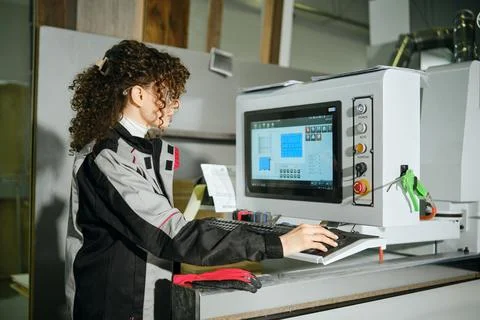 Woman operates machine in workshop during daytime while working on project .. Foto stock