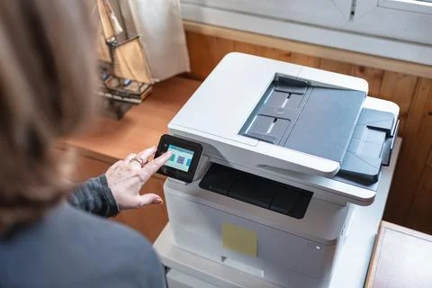 Woman operating a printer while teleworking from home remotely. Stock Photos
