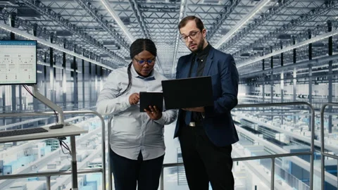 Woman optimizes microchip factory workflow with coworker, using EDA software Stock Footage 333379979