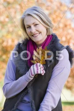 Woman outdoors at park holding leaves in hand smiling (selective focus) Stock-Fotos