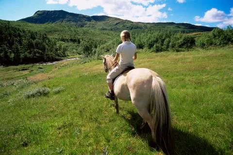 Woman outdoors riding horse in scenic location Stock Photos