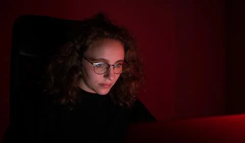 Woman overwhelmed while working at the computer at night. There is red light. Stock Photos
