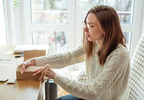 Woman packaging delivery box for small business e commerce Stock Photos