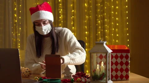 Woman packing Christmas present while having video chat during pandemic Stock Footage 144840521