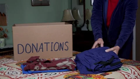 A woman packing clothes into a box for donations Stock Footage 262571276