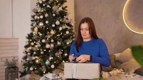 Woman packing gift boxes tying bow for new year near christmas tree Stock Footage 164485384