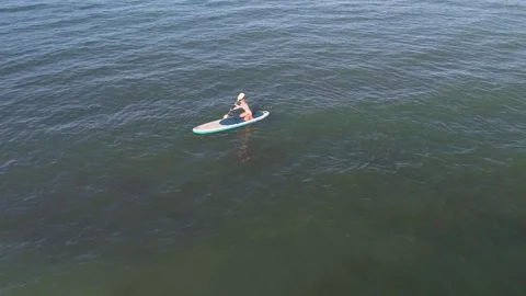 Woman paddling on a stand up paddle (SUP) in the ocean Stock Footage