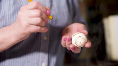 Woman paint Easter eggs in an authentic way with wax candles and paint. Home Stock Footage 131044181