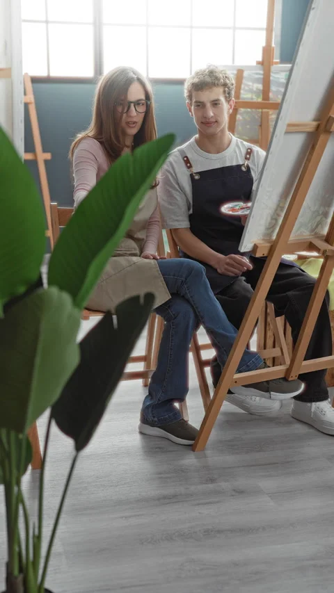 Woman painter points hand to canvas in studio while man holds palette and w.. Stock Footage 339258403