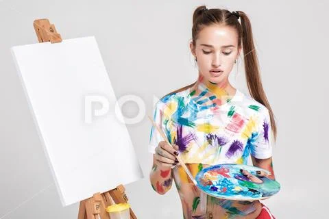 Woman painter soiled in colorful paint draws on canvas. Stock Photos