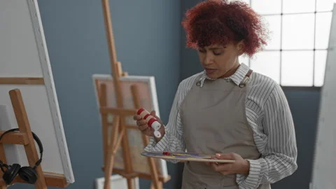Woman painter squeezing red paint tube onto wooden palette in art studio, h.. Stock Footage 337385212
