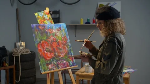 Woman paints flowers on canvas in the studio Stock Footage 125288053