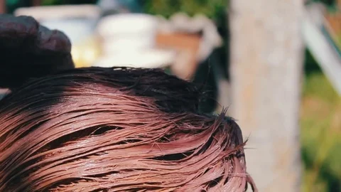 Woman paints her hair with brown paint in the summer on the street. Hair Stock Footage