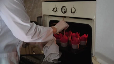 Woman pastry chef in the kitchen pulls out baking tray from a hot oven and Stock Footage 148941804
