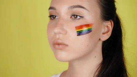 Woman with a pattern of a rainbow on her face close-up. Vídeo Stock 137889103