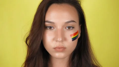 Woman with a pattern of a rainbow on her face close-up. Stockbeeldmateriaal 137889232