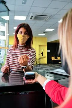 A woman pay using smartwatch using contactless technology - new normal Stock Photos