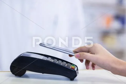 Woman Paying Bill Through Smartphone Using Nfc Technology In Pharmacy