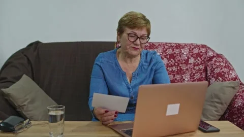 A woman pays for services while sitting at home on the couch at the computer. Stock Footage 145256232