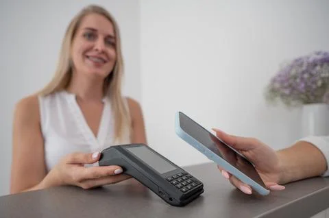 A woman pays using a non -contact payment of the NFC used by a smartphone. Stock Photos