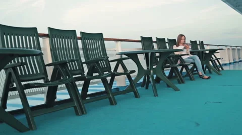 Woman with pc digital tablet sitting on deck of cruise ship at sunrise Stock Footage