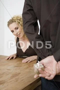 A woman peeking at the present in a man's hands Stock Photos