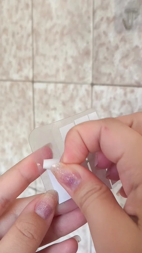 A woman peels off a protective layer from a double-sided adhesive tape on towel 動画素材 315153264