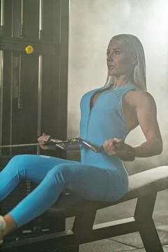 Woman performing block pull exercise to the waist in a fitness studio during a Stock Photos