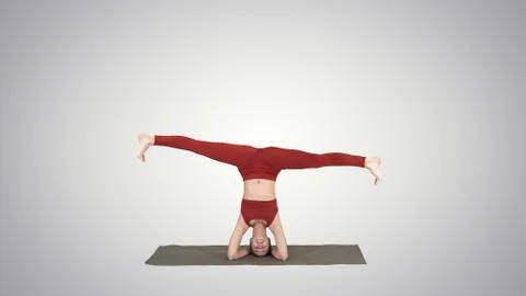 Woman performing a headstand with split on gradient background. Stock Photos
