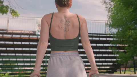 Woman performing pull ups on parallel bars in outdoor park with visible back Stock Footage 345843565
