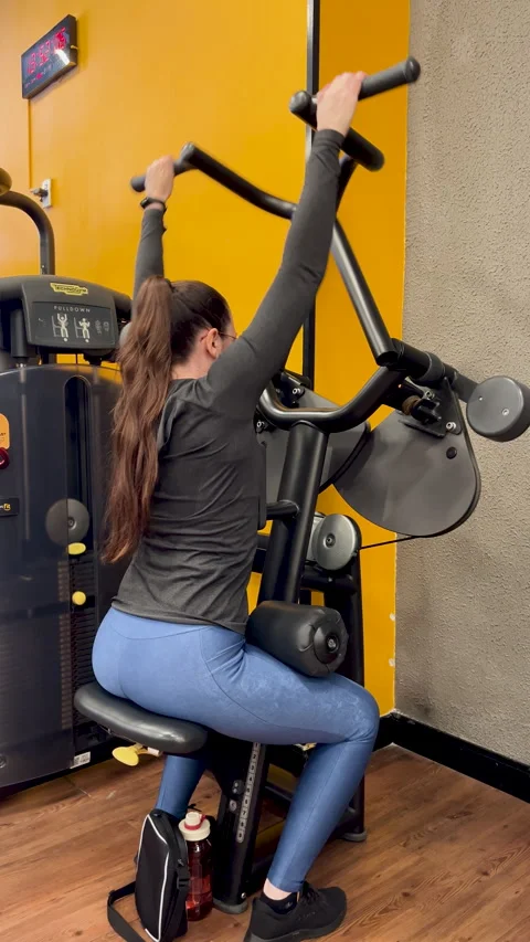 Woman performing seated lat pulldown side view - back pull gym training Stock Footage 337381130