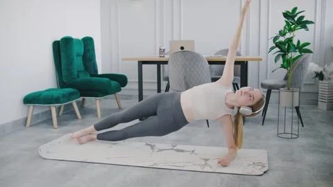 Woman performing a side plank exercise at home in a modern and spacious indoor Stock Footage 302662297