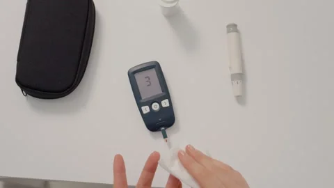 Woman performs blood sugar test using glucometer at home for diabetes management Stock Footage 346703604