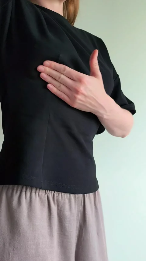 Woman performs a breast self examination feeling for lumps with both hands... 動画素材 336975197