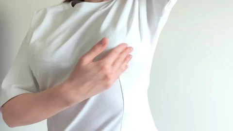 Woman performs a breast self examination feeling for lumps under her shirt... 動画素材 337774139