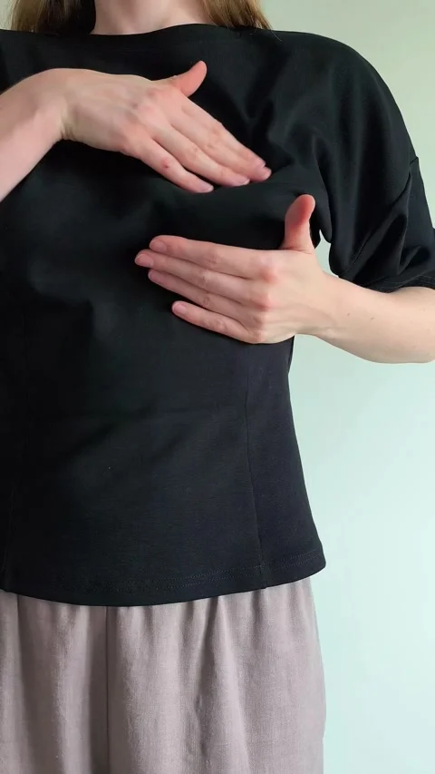 Woman performs a breast self examination feeling for lumps with both hands... 動画素材 337774163